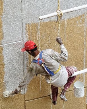 image of a man painting a building